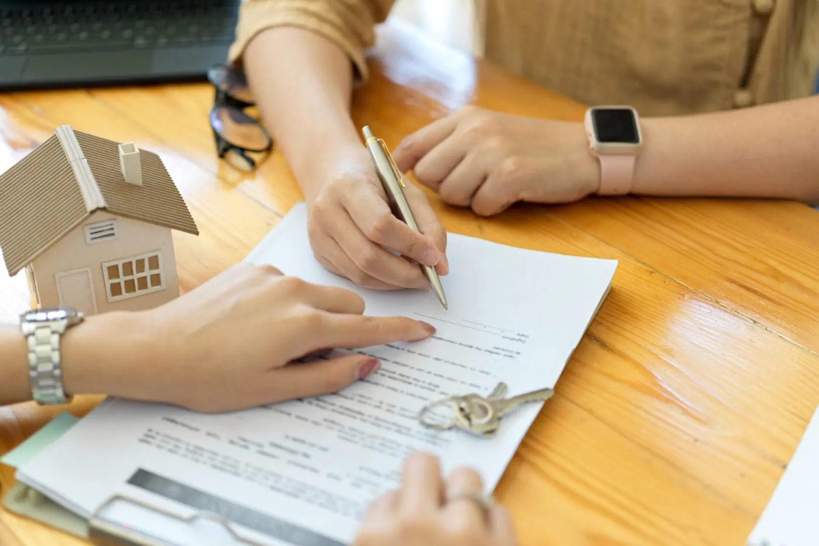 Signing real estate contract at wooden table.